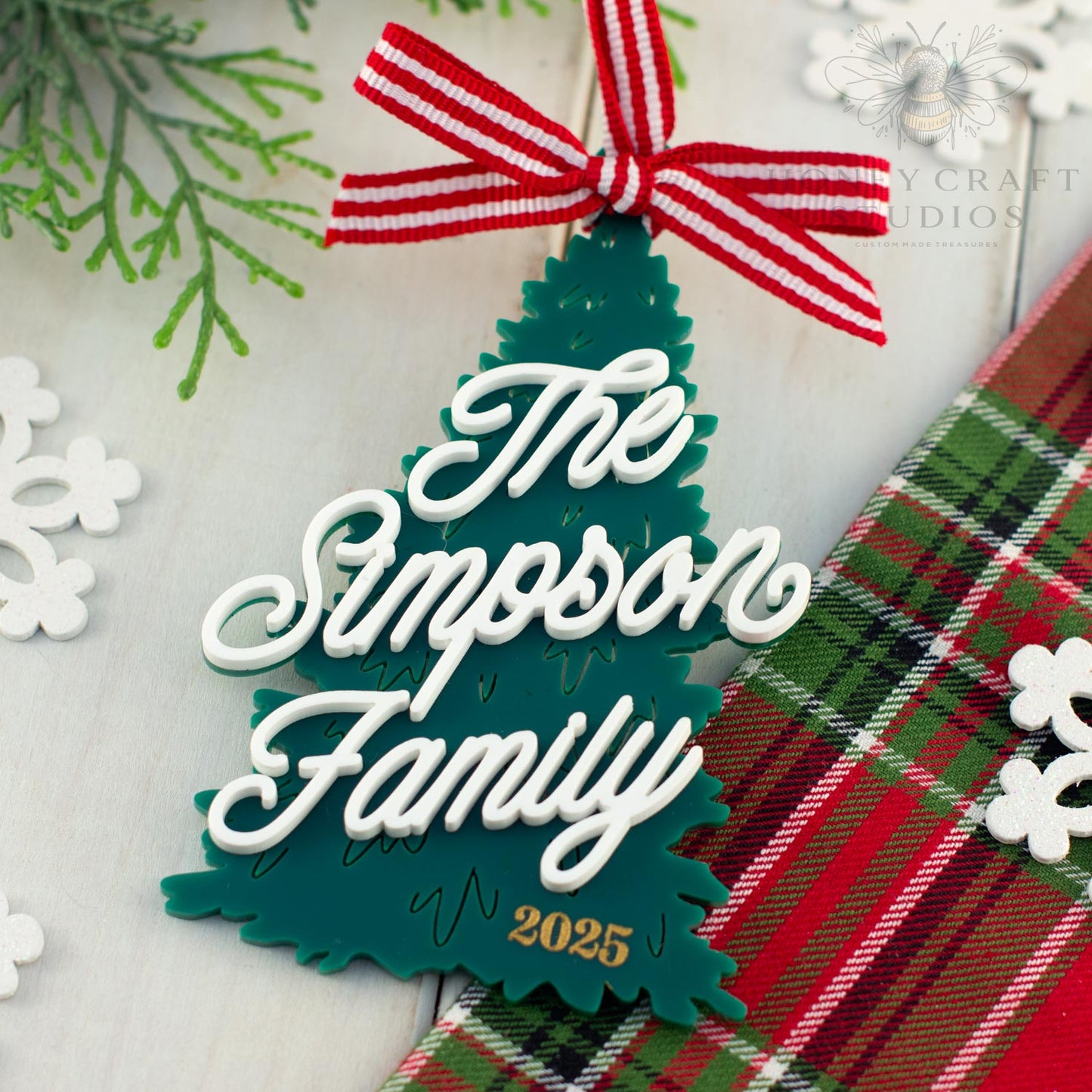 Christmas tree-shaped ornament with 'The Simpson Family 2025' text on a plaid fabric background.