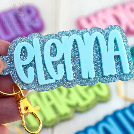 Personalized name keychain in ice blue and glitter acrylic, ideal for labeling kids’ backpacks or school bags.
