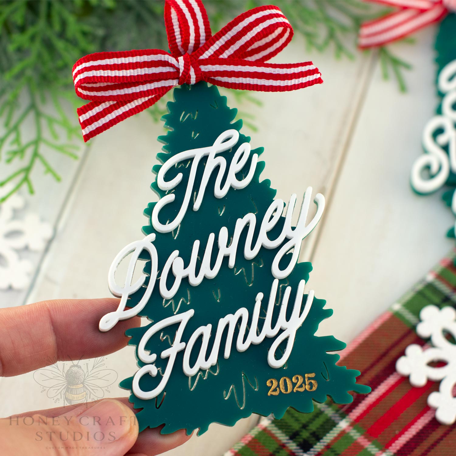 Decorative Christmas tree ornament with 'The Downey Family 2025' text and a red and white bow.