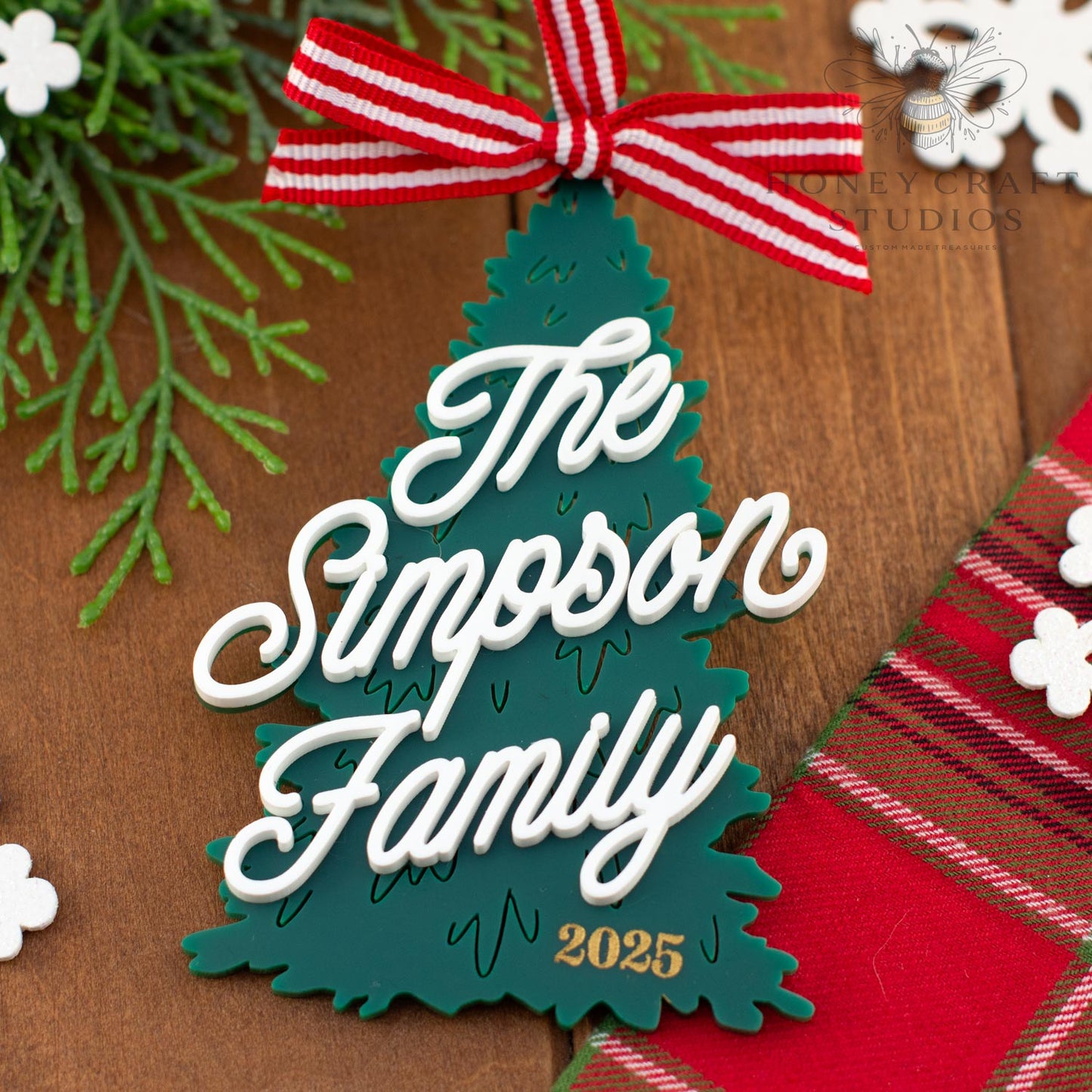 Decorative Christmas ornament with 'The Simpson Family 2025' text on a wooden background.