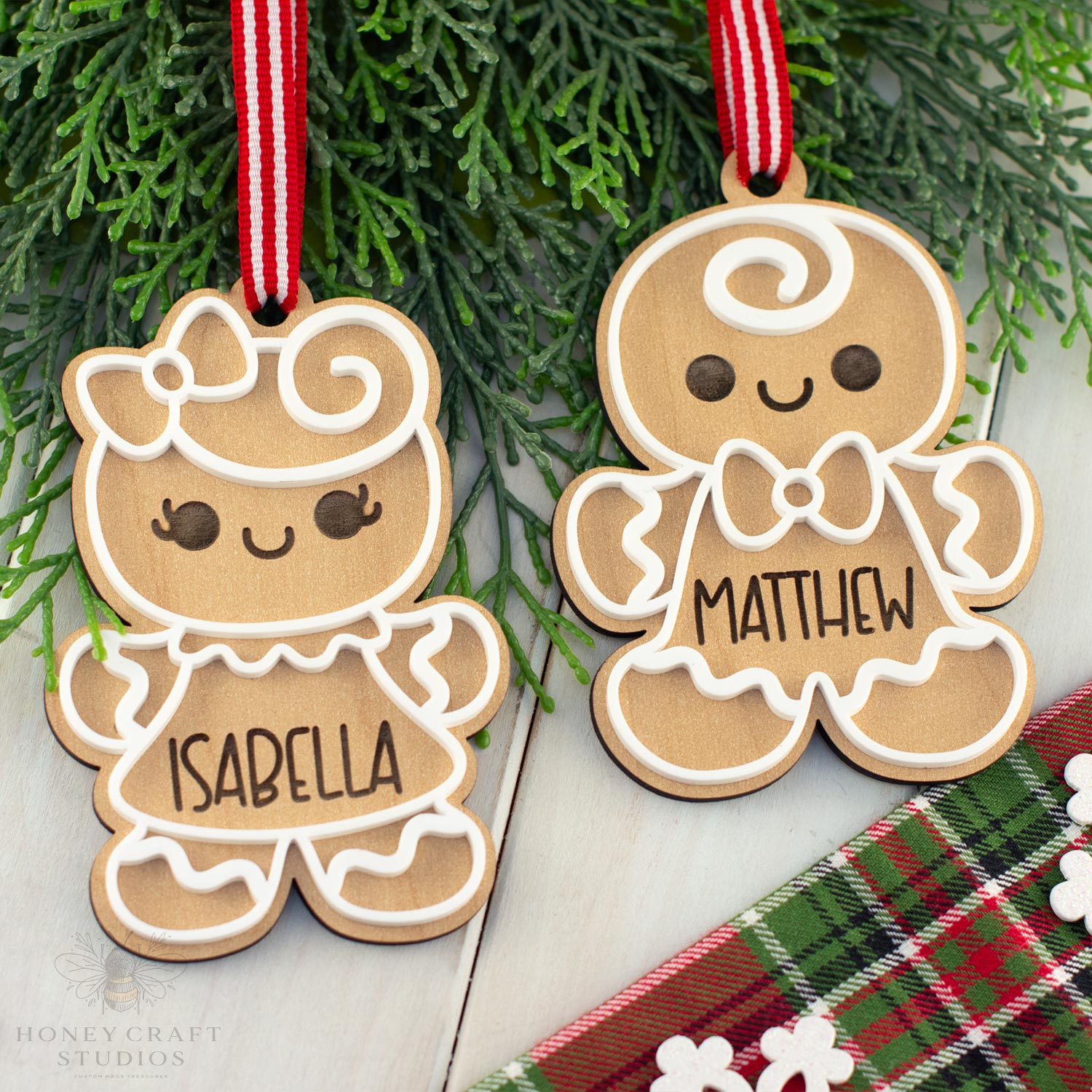 Two wooden gingerbread cookie ornaments with names 'Isabella' and 'Matthew' hanging on a branch.
