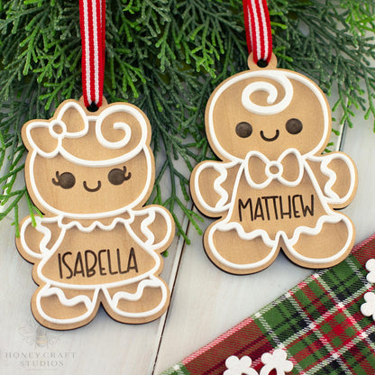 Two wooden gingerbread cookie ornaments with names 'Isabella' and 'Matthew' hanging on a branch.
