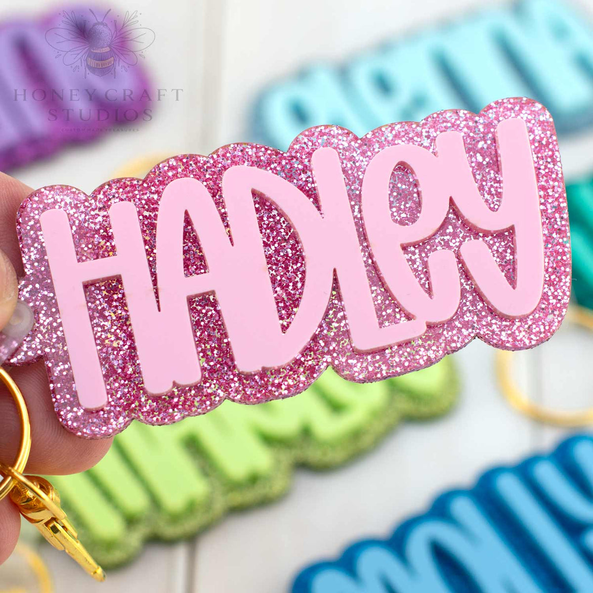 Custom name keychain in pink glitter acrylic with bold lettering, great back-to-school gift for girls.