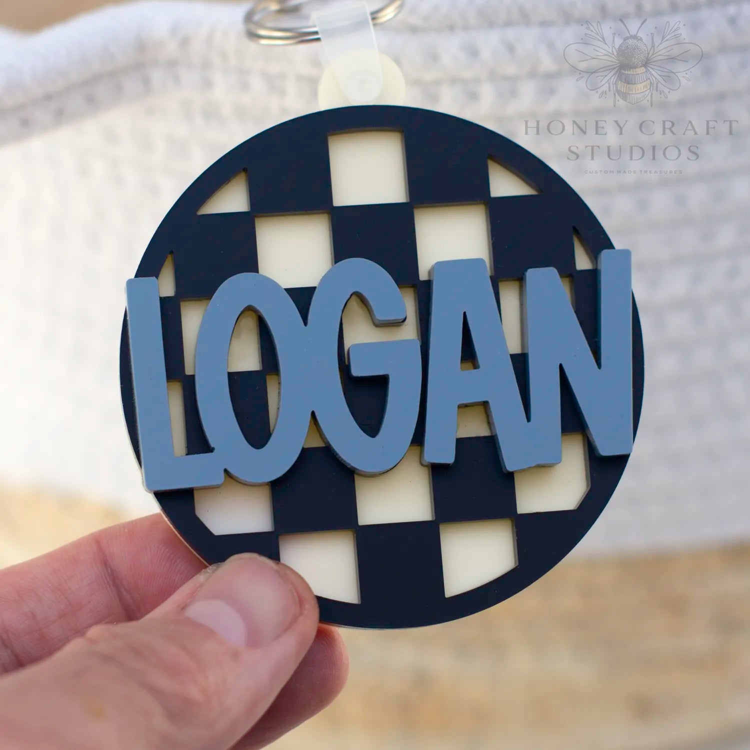 Custom black acrylic name tag with slate blue name, laser-cut and layered for bold personalization.