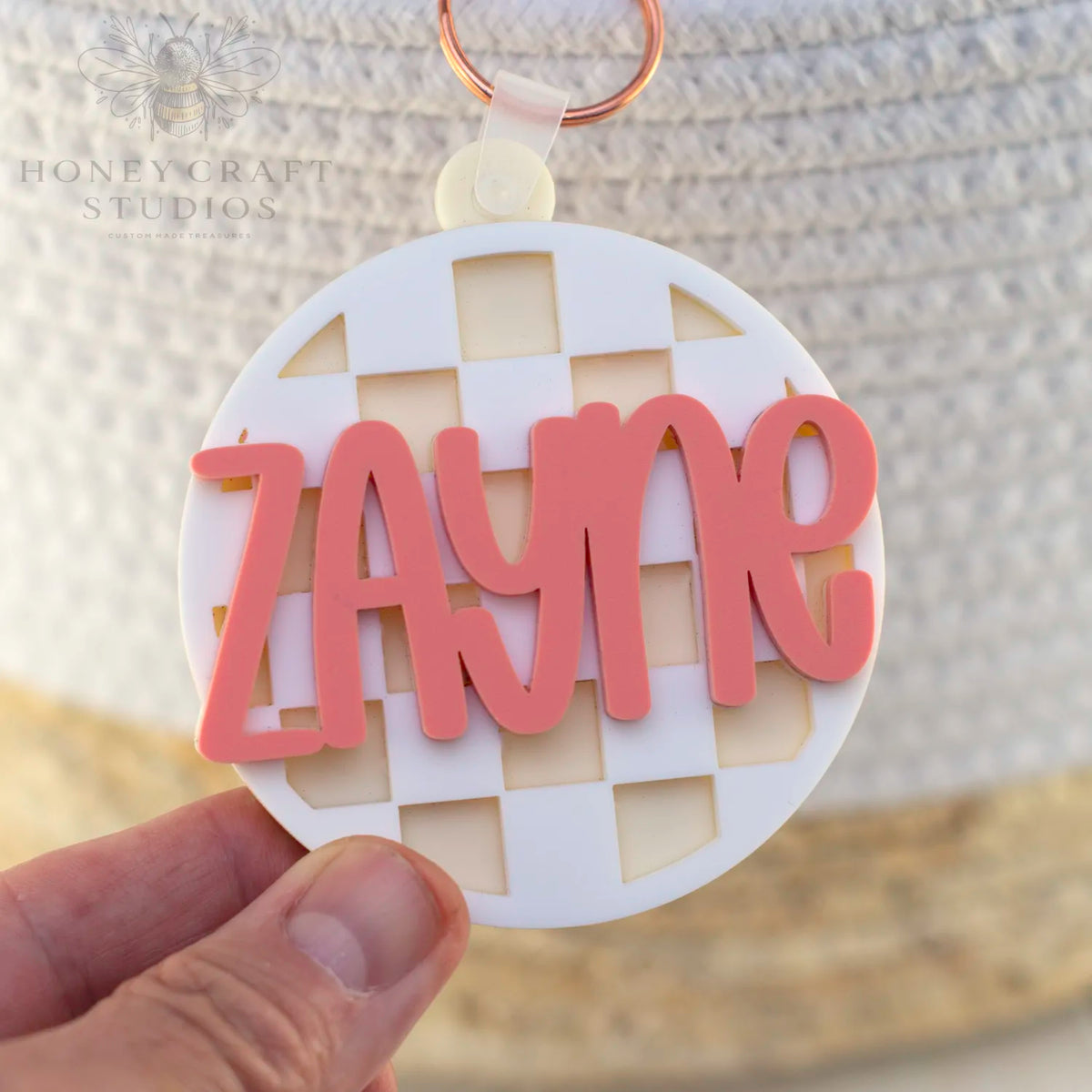 Personalized white checkered acrylic name tag with layered pink text, stylish ID for backpacks and lunchboxes.