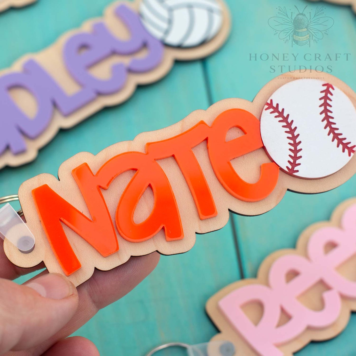 Custom baseball name keychain with orange acrylic lettering and engraved wood base, featuring baseball icon