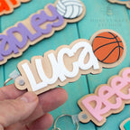 Personalized basketball name tag keychain with white acrylic name on wood backing and basketball design