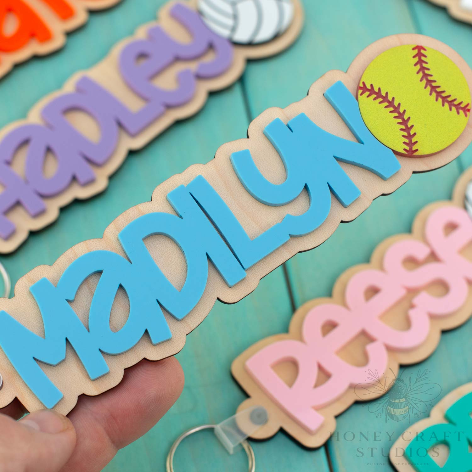 Custom softball name keychain with blue acrylic name and bright yellow softball icon on wood backing