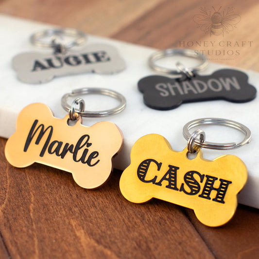 Set of personalized bone dog tags in gold, black, and silver with engraved pet names Marlie, Cash, Augie, and Shadow