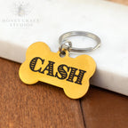 Gold engraved bone dog tag with name Cash in bold font and attached key ring