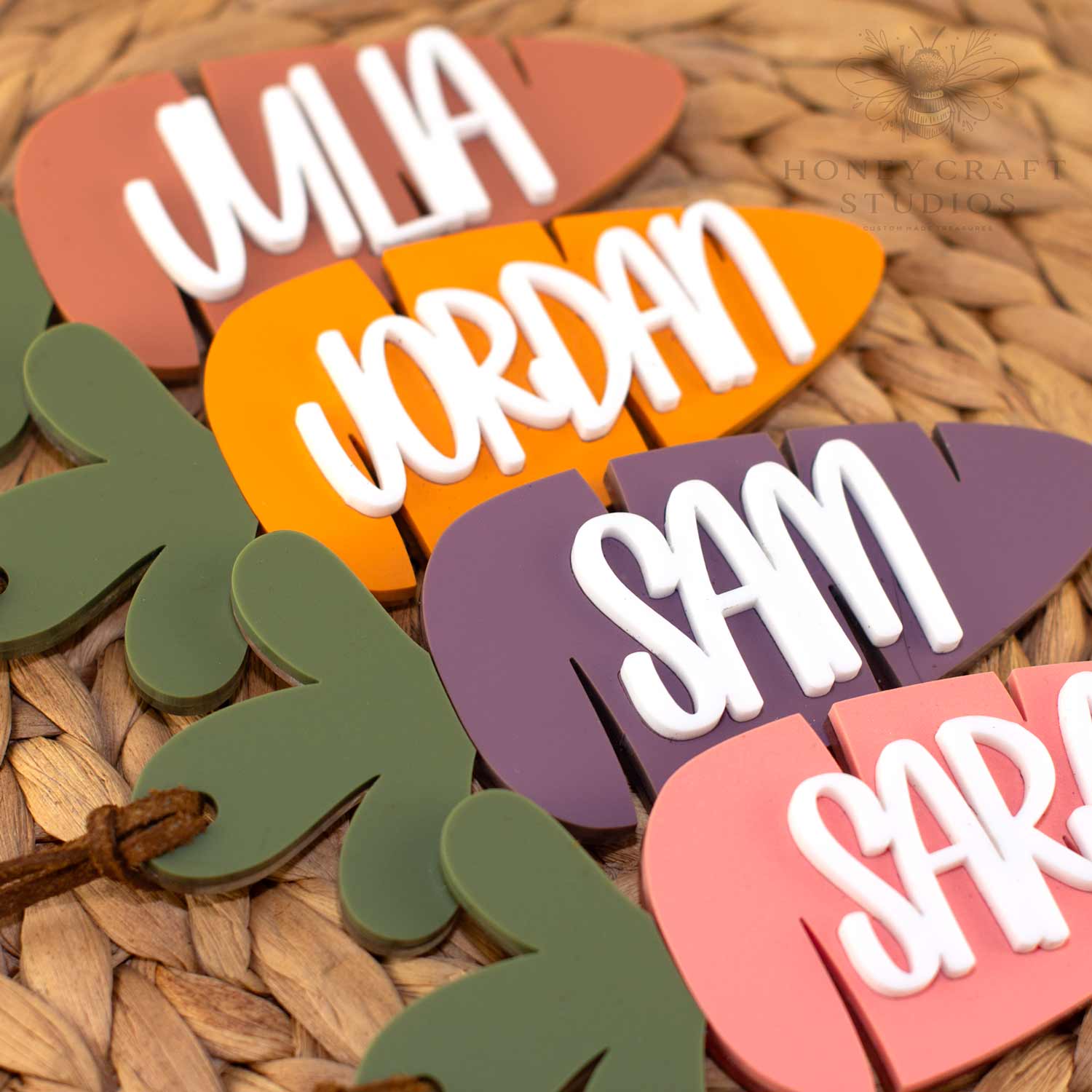 Personalized acrylic carrot Easter basket tags with raised white names in assorted colors, displayed on a woven basket background