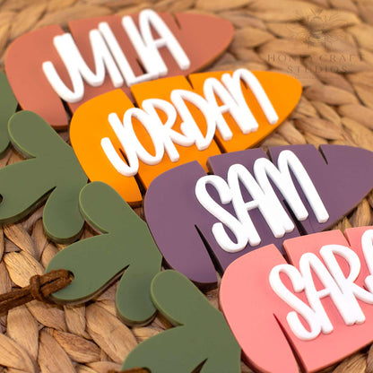 Personalized acrylic carrot Easter basket tags with raised white names in assorted colors, displayed on a woven basket background