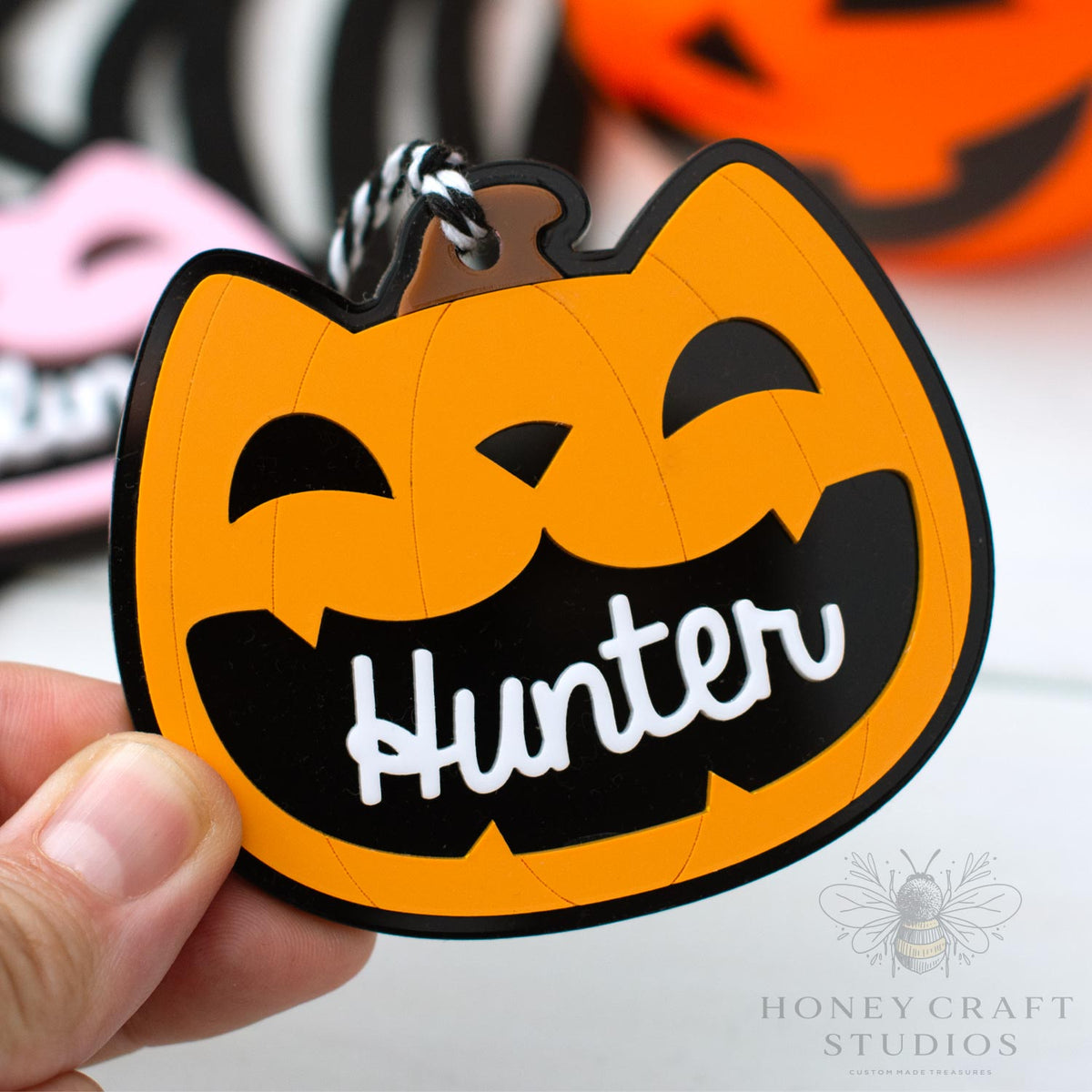 Halloween-themed cat lack-o-lantern  keychain with a pumpkin design and 'Hunter' text, held by a hand.