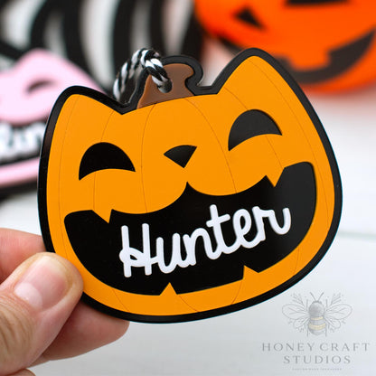 Halloween-themed cat lack-o-lantern  keychain with a pumpkin design and 'Hunter' text, held by a hand.