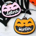 Halloween-themed cat lack-o-lantern name tags with 'Selina' and 'Hunter' on a white background.