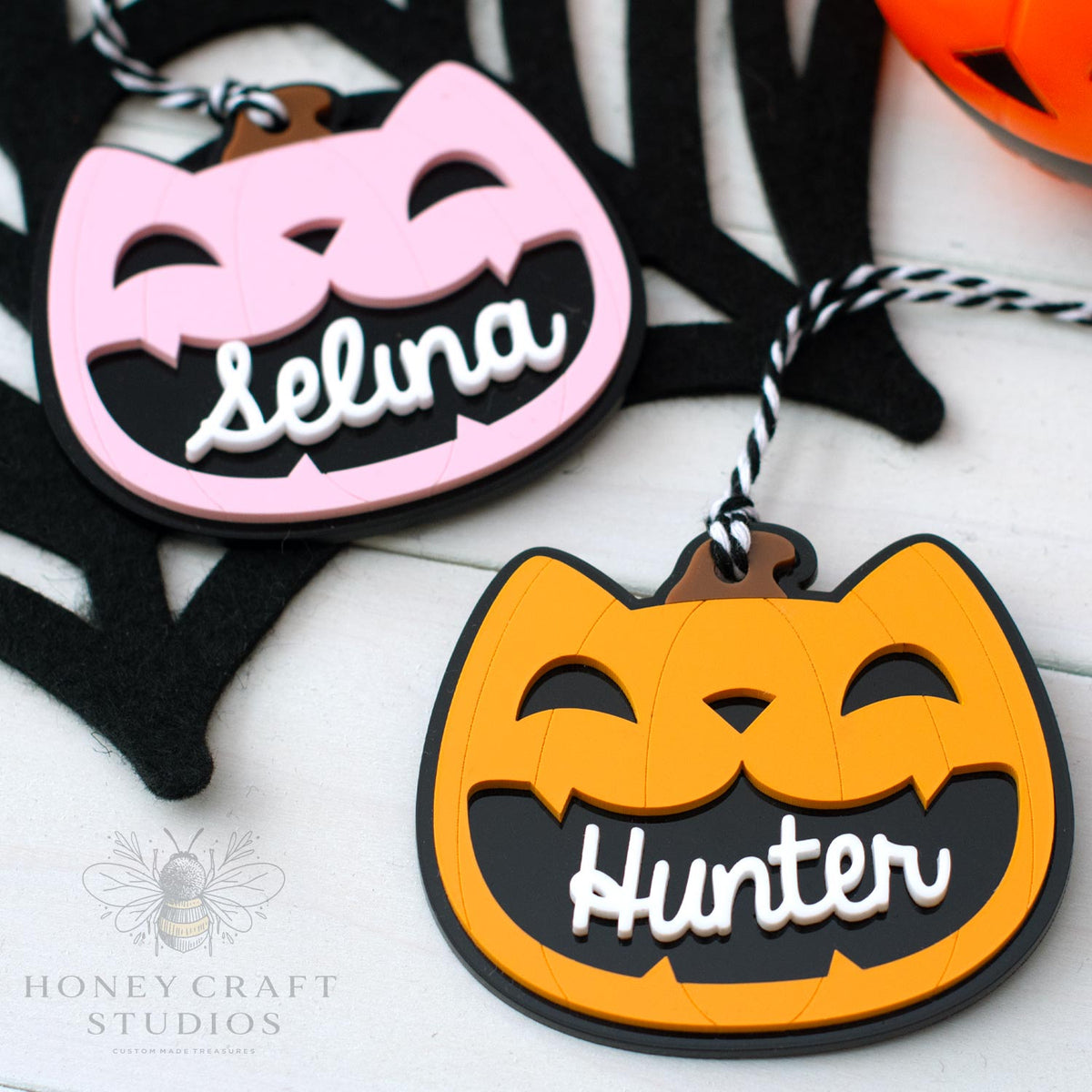 Halloween-themed cat lack-o-lantern name tags with 'Selina' and 'Hunter' on a white background.