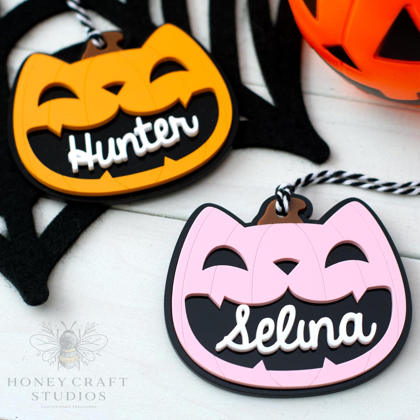 Halloween-themed cat lack-o-lantern name tags with 'Hunter' and 'Selina' on a white background