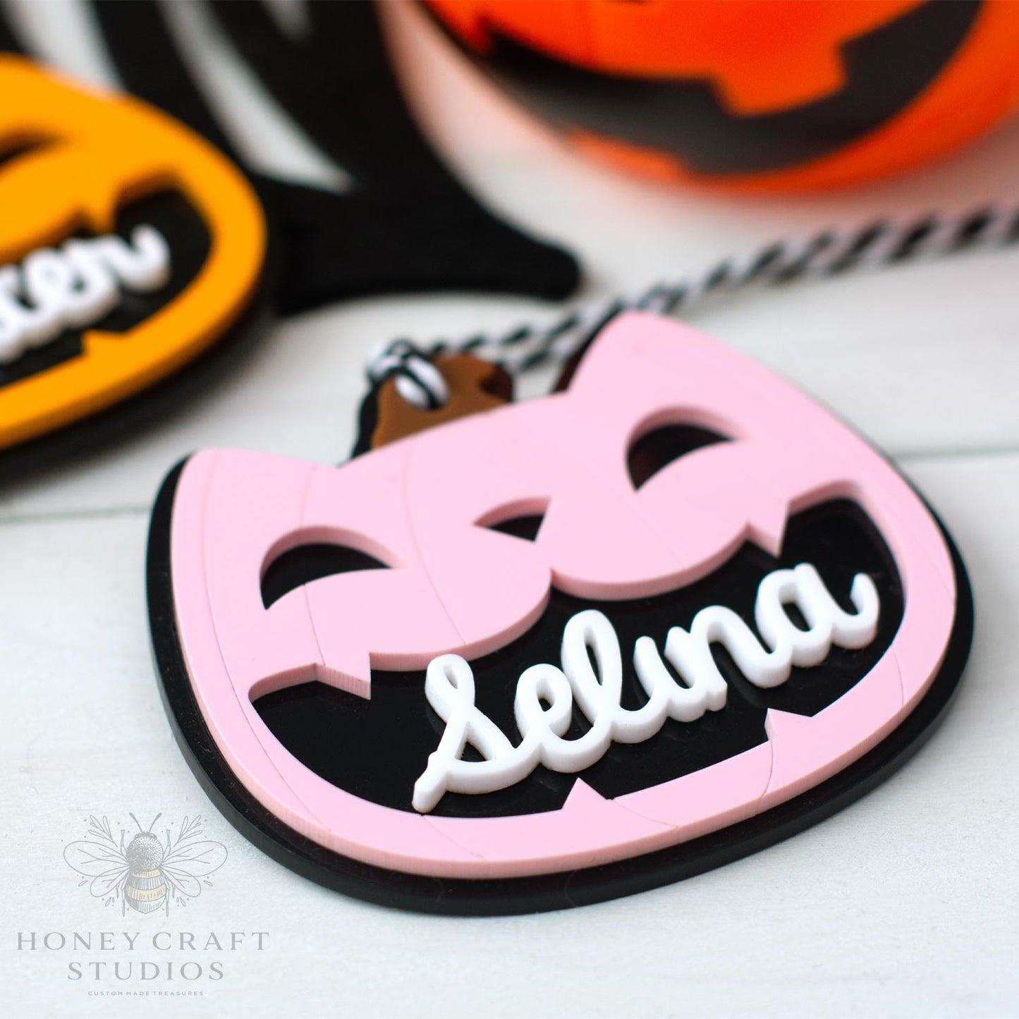 Pink and black Halloween-themed cat lack-o-lantern name tag with 'Selina' on a white background, featuring Honey Craft Studios logo.