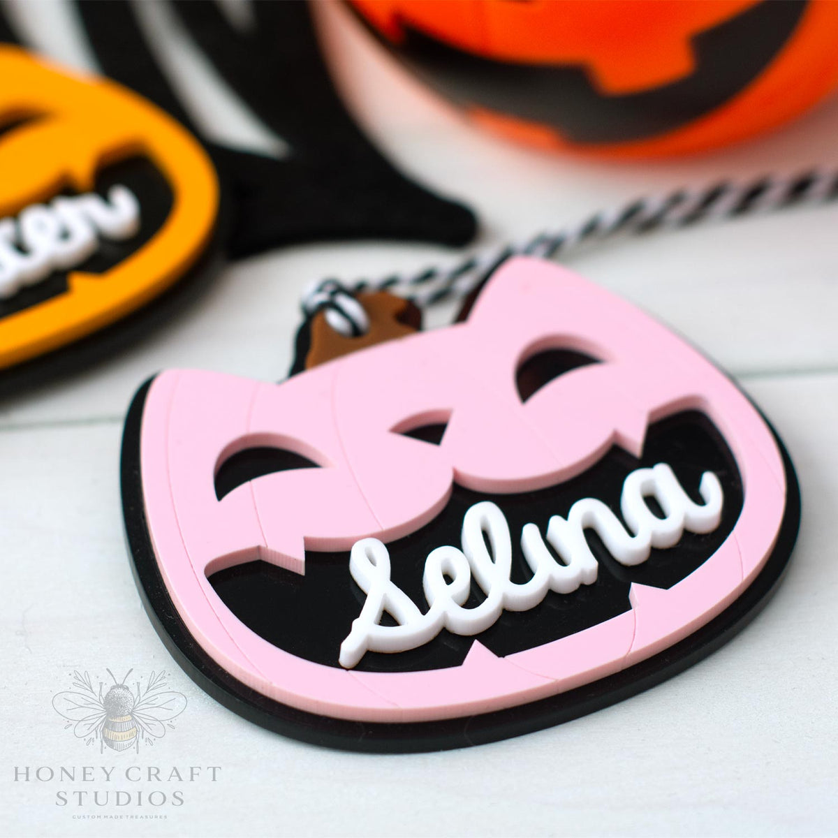 Pink and black Halloween-themed cat lack-o-lantern name tag with 'Selina' on a white background, featuring Honey Craft Studios logo.