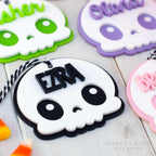 Decorative skull-shaped cookies with personalized names on a white surface.