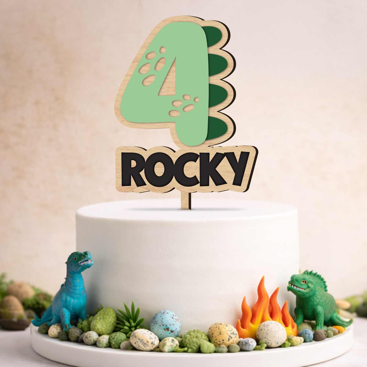 Personalized dinosaur number cake topper with acrylic green dino number 4 and custom engraved name Rocky on a white birthday cake. Made by Honey Craft Studios.