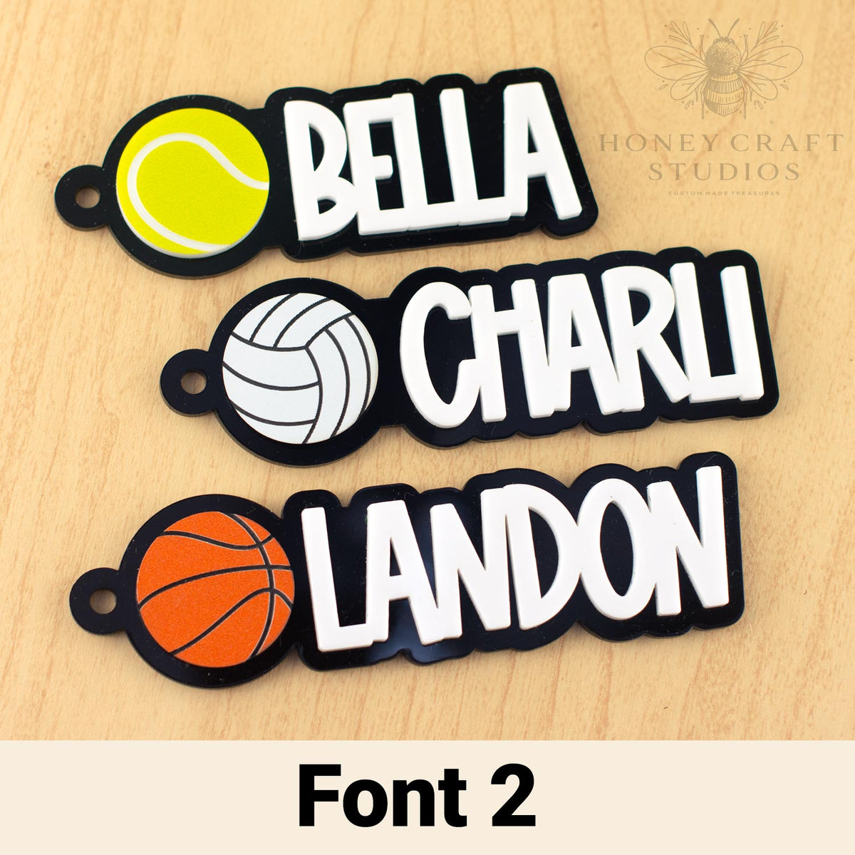 Three personalized name tags with sports-themed designs, featuring 'Bella', 'Charli', and 'Landon'.