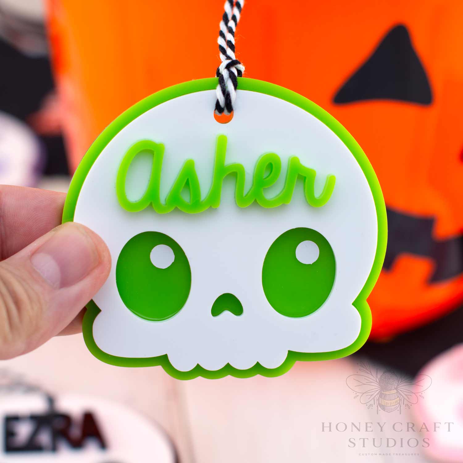 Skull-shaped name tag with 'Asher' on a Halloween-themed background