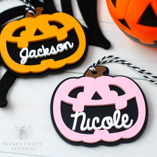 Halloween-themed name tags shaped like pumpkins with 'Jackson' and 'Nicole' on a white background.