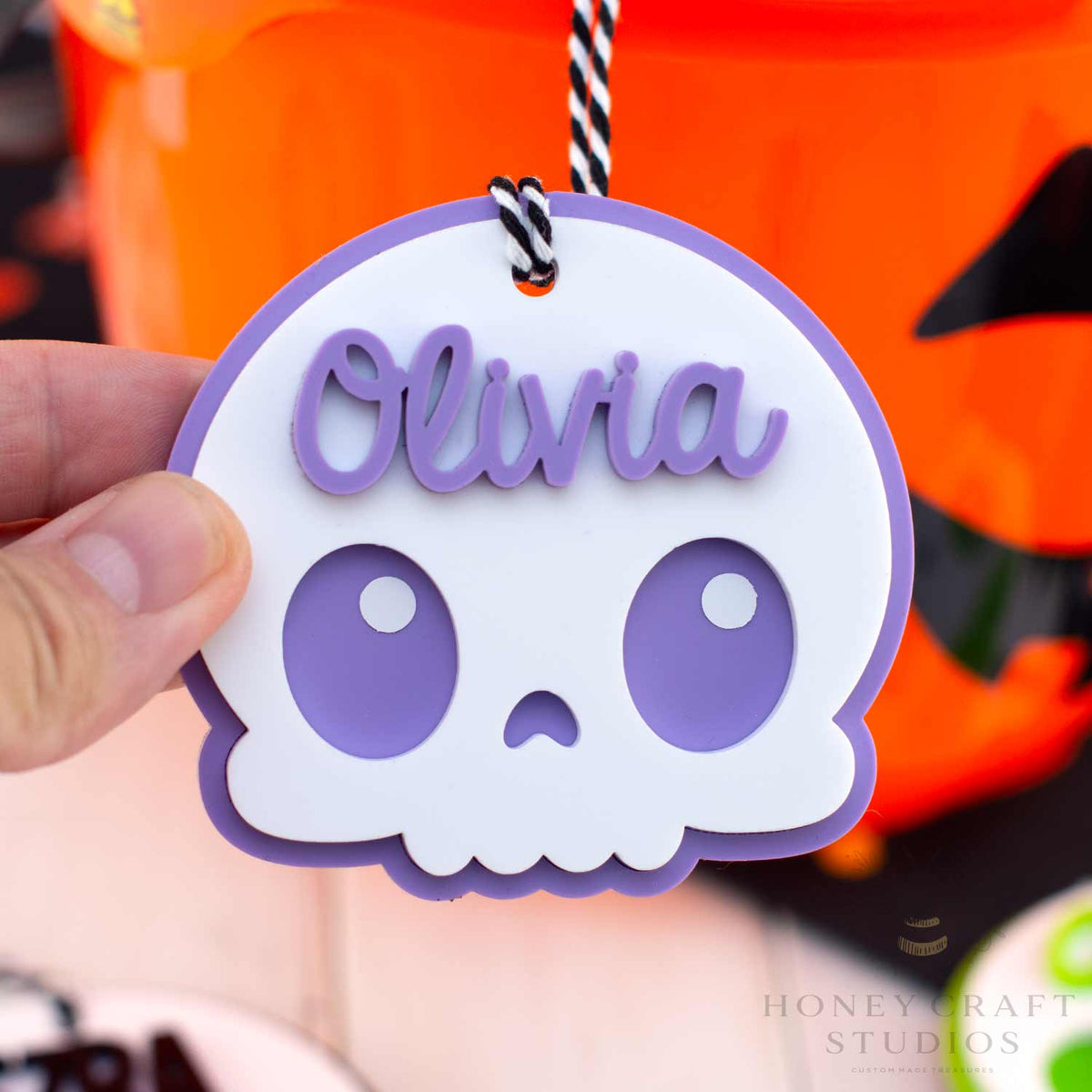 Skull-shaped name tag with 'Olivia' on a Halloween-themed background