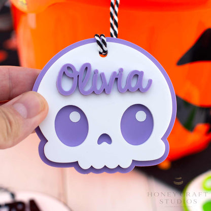 Skull-shaped name tag with 'Olivia' on a Halloween-themed background