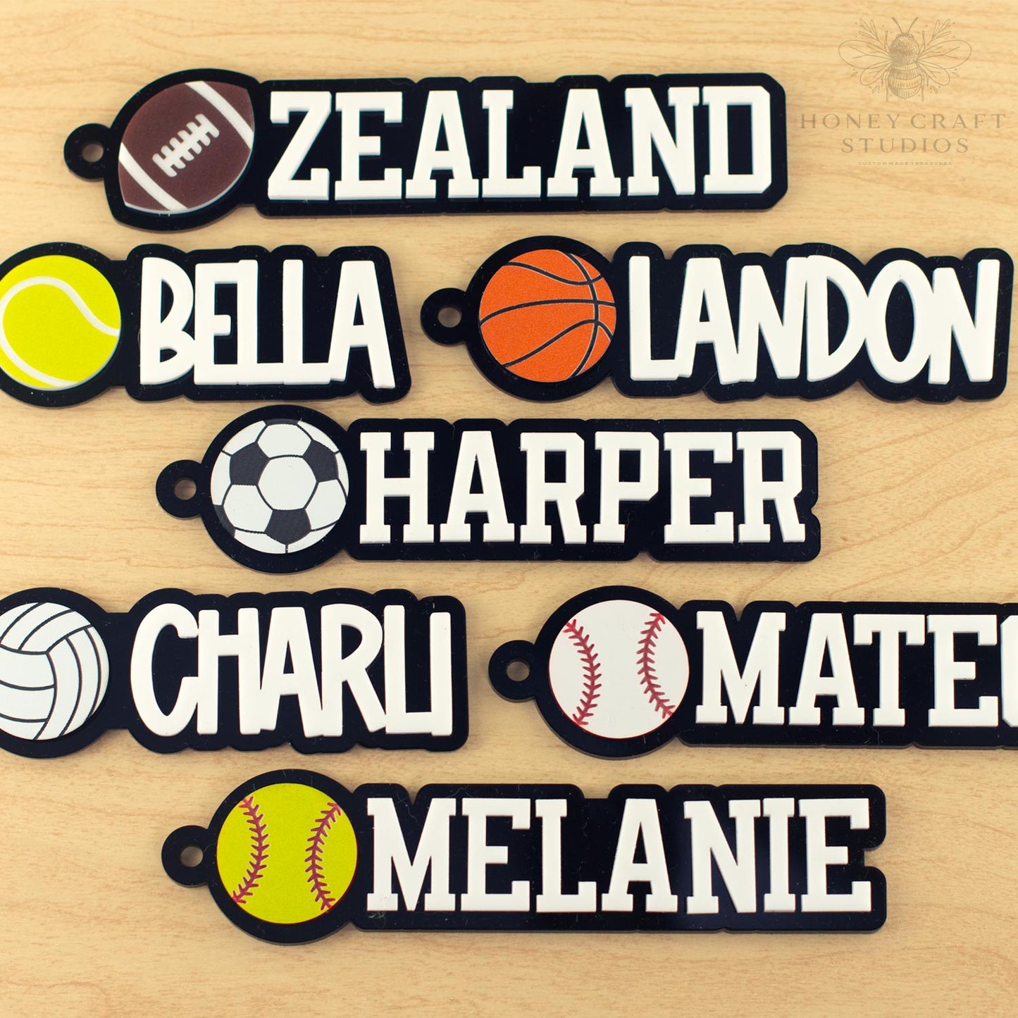 Assorted personalized sports name tags with names and different ball icons including football, basketball, tennis, soccer, volleyball, and baseball.
