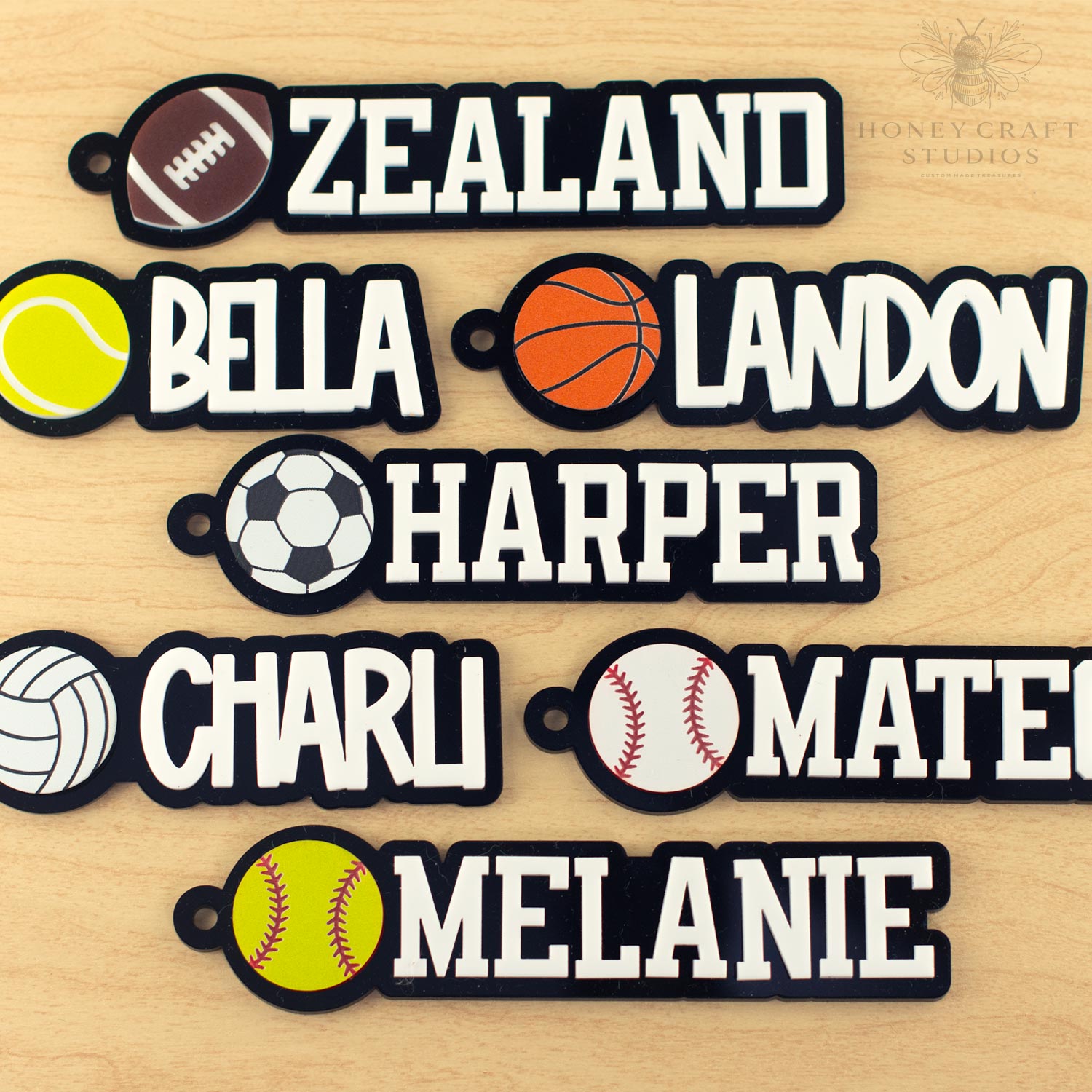 Assorted personalized sports name tags with names and different ball icons including football, basketball, tennis, soccer, volleyball, and baseball.