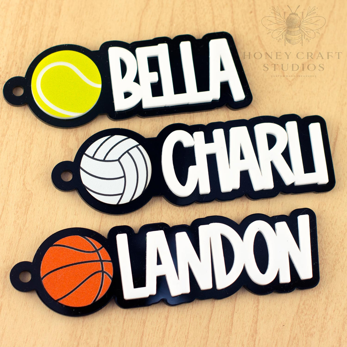 Three personalized sports bag tags for kids with tennis, volleyball, and basketball icons and bold names in white letters.
